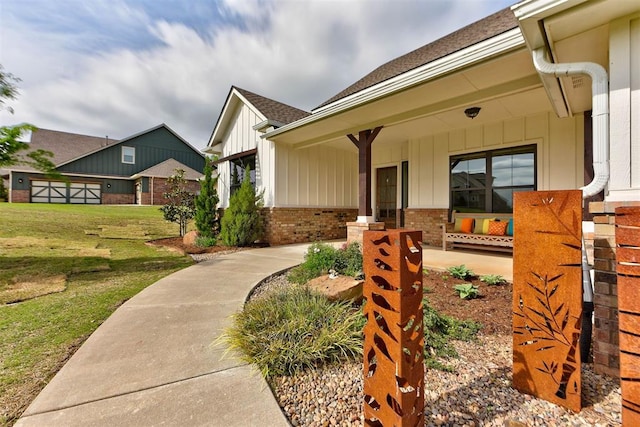 view of front of house featuring brick siding, a front yard, board and batten siding, and covered porch