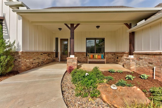 entrance to property with brick siding and a porch