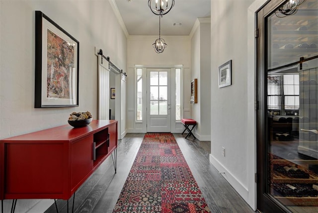 foyer entrance with dark wood finished floors, a barn door, baseboards, visible vents, and crown molding