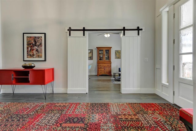 entrance foyer with a barn door, a wealth of natural light, wood finished floors, and baseboards