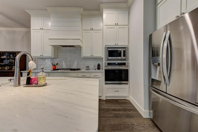 kitchen featuring white cabinets, stainless steel appliances, dark wood-style floors, tasteful backsplash, and ornamental molding
