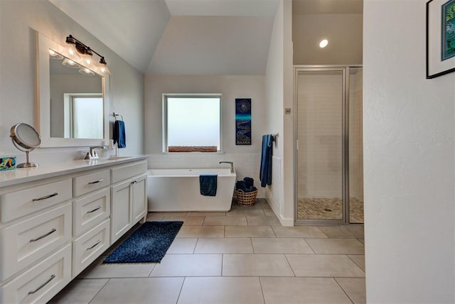 bathroom with tile patterned floors, a stall shower, a freestanding tub, vanity, and lofted ceiling