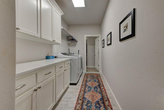 clothes washing area with cabinet space, independent washer and dryer, and baseboards