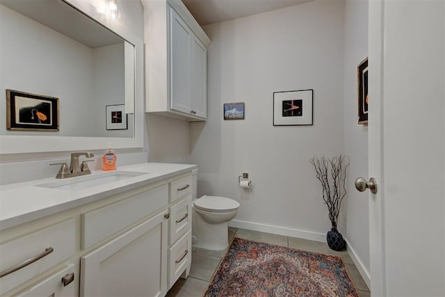 half bath with baseboards, vanity, tile patterned flooring, and toilet
