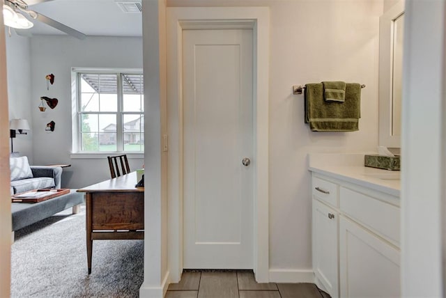ensuite bathroom featuring visible vents, a ceiling fan, vanity, ensuite bath, and baseboards