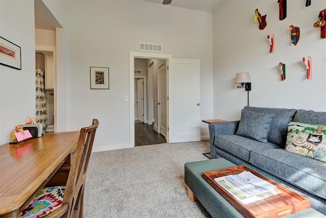 carpeted living area featuring a towering ceiling, baseboards, and visible vents