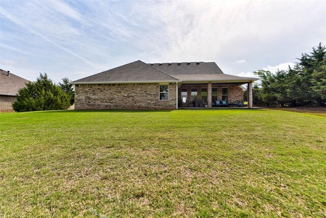 back of house featuring a lawn, brick siding, and a patio area