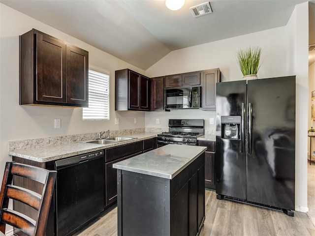 kitchen with black appliances, lofted ceiling, light countertops, a center island, and light wood-style flooring