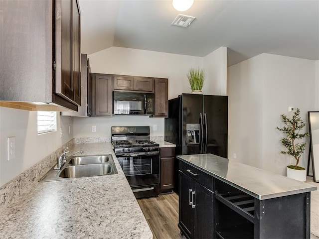 kitchen with black appliances, a sink, light wood-style floors, light countertops, and lofted ceiling