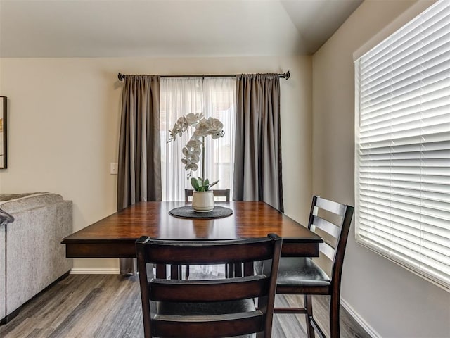 dining area featuring wood finished floors, plenty of natural light, lofted ceiling, and baseboards