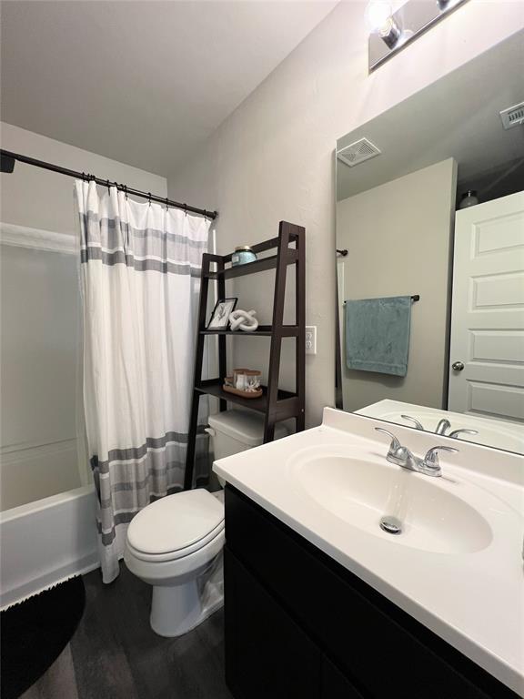 full bath featuring toilet, vanity, wood finished floors, and shower / bath combo