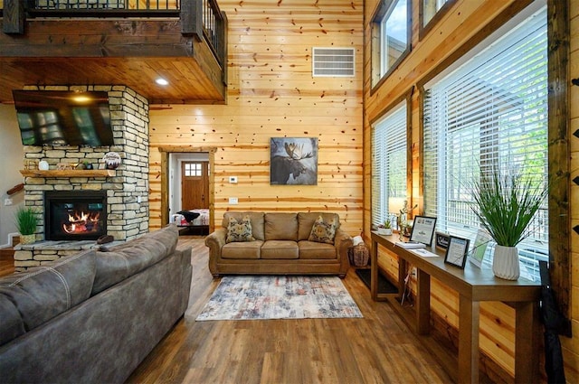 living area with wooden walls, wood finished floors, and a healthy amount of sunlight