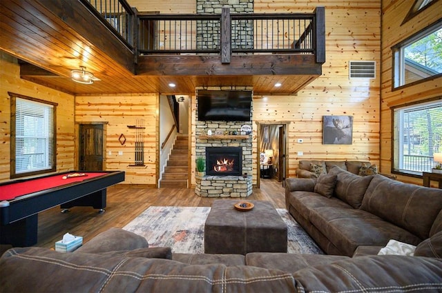 living area with wood walls, a towering ceiling, billiards, and wood finished floors