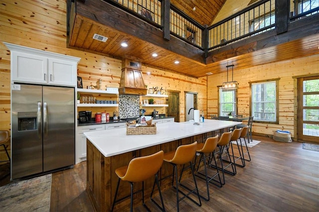 kitchen featuring open shelves, wood walls, dark wood-type flooring, and stainless steel fridge with ice dispenser