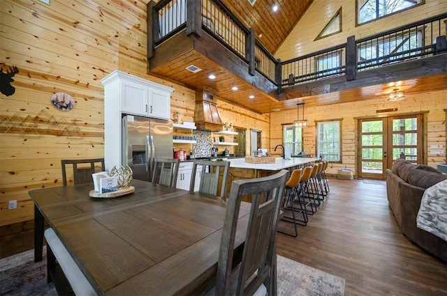 dining room featuring a wealth of natural light, wood walls, high vaulted ceiling, and dark wood finished floors