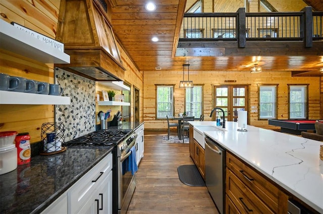 kitchen with stainless steel appliances, open shelves, wooden walls, a sink, and dark wood-style flooring