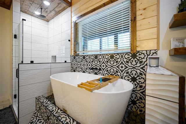 bathroom with a soaking tub, a stall shower, and tile walls