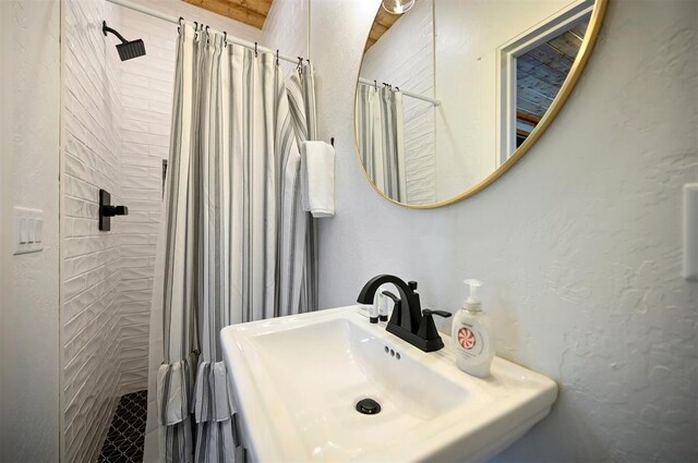bathroom featuring a tile shower and a sink