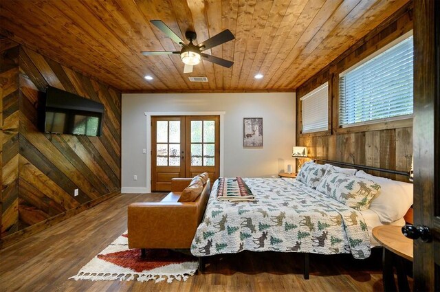 bedroom featuring wood finished floors, wooden walls, wooden ceiling, baseboards, and visible vents