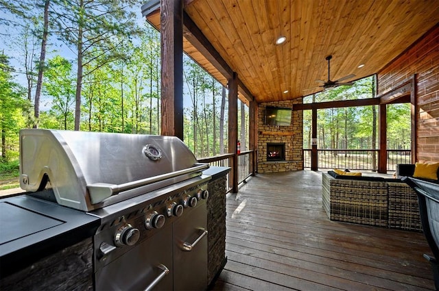 sunroom featuring exterior kitchen, an outdoor stone fireplace, and ceiling fan