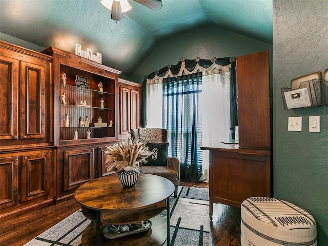 sitting room featuring a textured wall, lofted ceiling, wood finished floors, a textured ceiling, and a ceiling fan