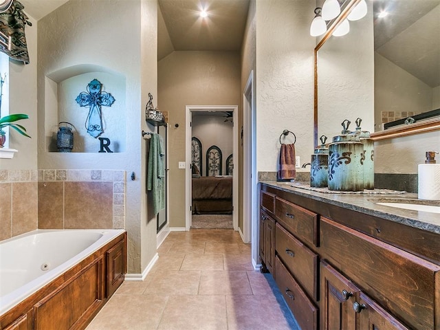 bathroom with vanity, a textured wall, lofted ceiling, a whirlpool tub, and connected bathroom
