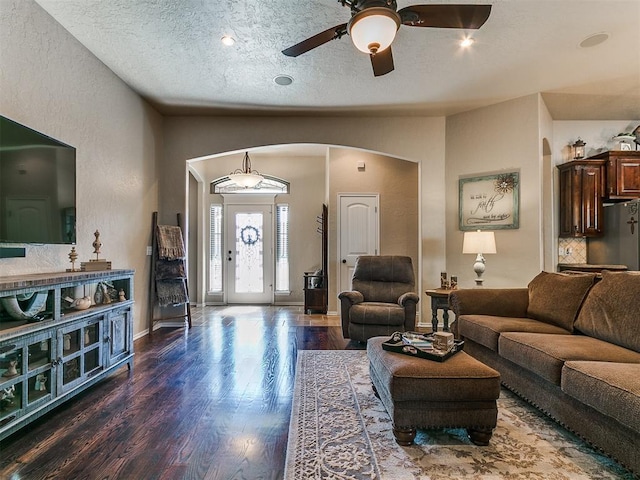 living area with arched walkways, a textured ceiling, a ceiling fan, baseboards, and wood finished floors