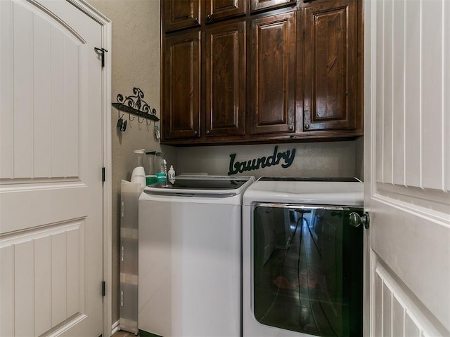 clothes washing area featuring cabinet space, a textured wall, and washing machine and dryer