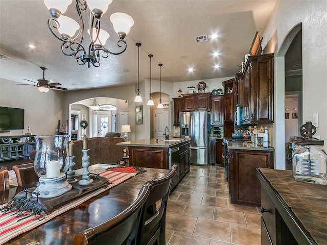 dining area featuring arched walkways, ceiling fan with notable chandelier, tile patterned floors, and visible vents