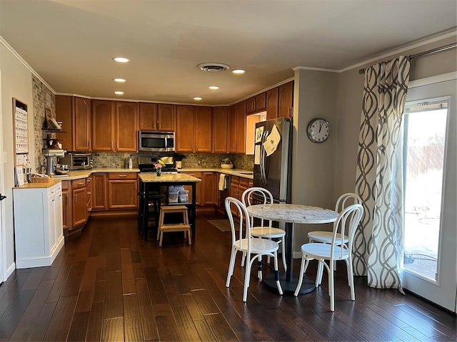2813 Clermont Pl, Oklahoma City, OK 73116 - kitchen featuring appliances with stainless steel finishes, light countertops, dark wood-style flooring, decorative backsplash, and crown molding