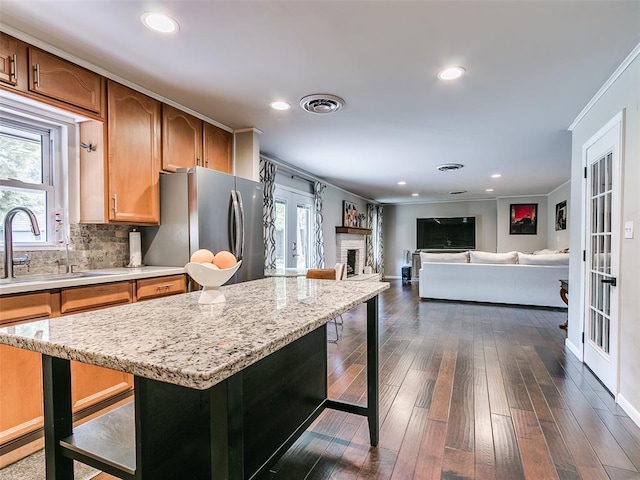 2813 Clermont Pl, Oklahoma City, OK 73116 - kitchen featuring freestanding refrigerator, a kitchen breakfast bar, dark wood finished floors, ornamental molding, and open floor plan