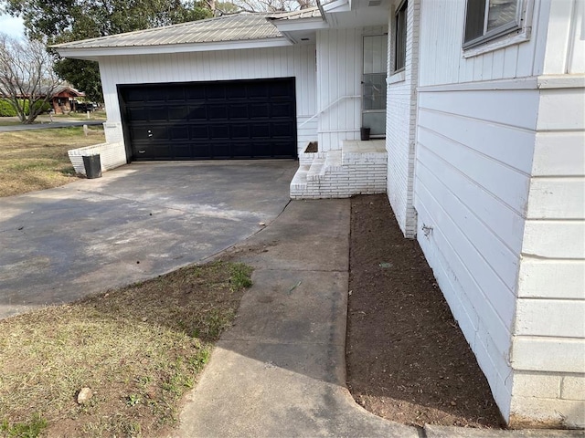view of side of home with driveway, metal roof, and a garage