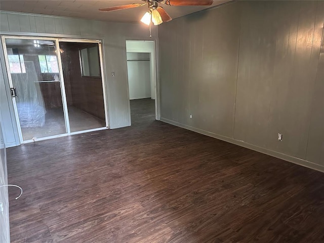 unfurnished bedroom featuring baseboards, a ceiling fan, dark wood-style floors, and a closet