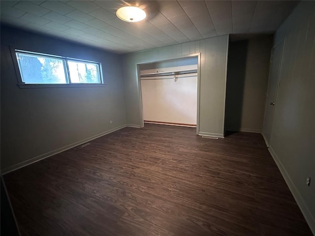 unfurnished bedroom featuring dark wood finished floors, a closet, and baseboards