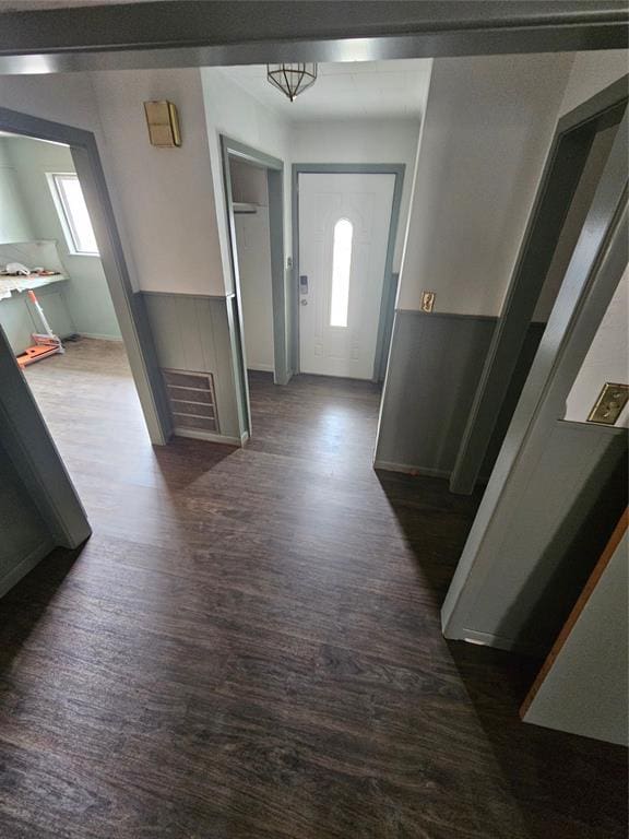corridor featuring dark wood finished floors, baseboards, and visible vents