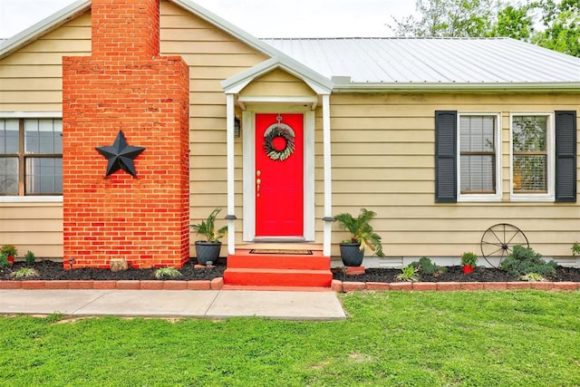 view of exterior entry featuring a yard and metal roof