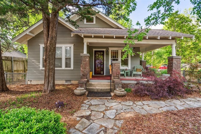 view of front facade featuring fence, crawl space, roof with shingles, and a porch