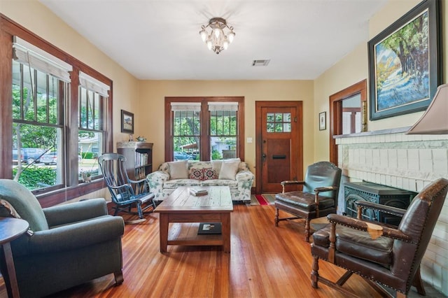 living area featuring healthy amount of natural light, light wood-style floors, and a chandelier