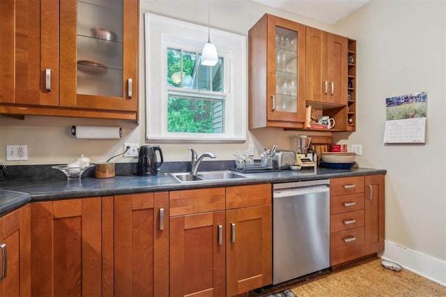 kitchen featuring dishwasher, brown cabinets, a sink, and dark countertops