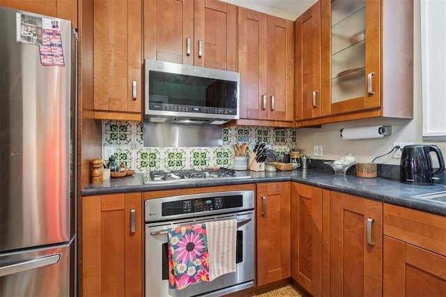 kitchen featuring stainless steel appliances, brown cabinets, and dark countertops