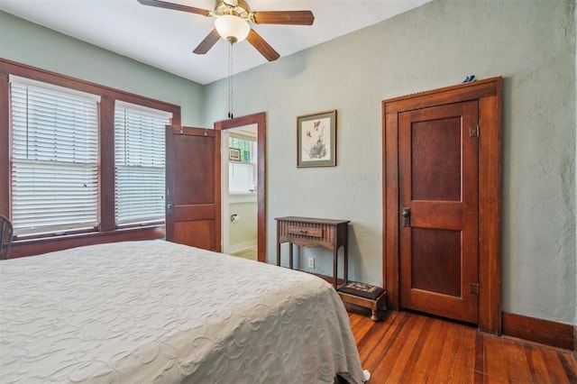 bedroom with wood finished floors, baseboards, a ceiling fan, and a textured wall