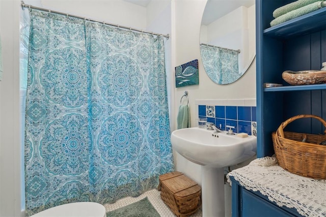 full bath with tile walls, toilet, curtained shower, and a sink