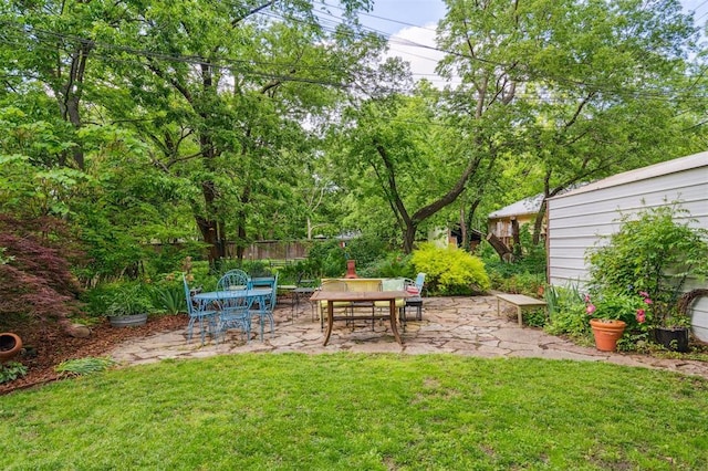 view of grassy yard featuring a patio area and outdoor dining area