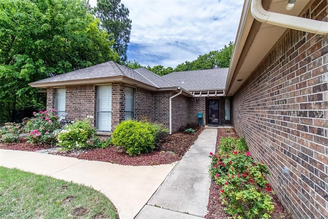 property entrance with brick siding and roof with shingles