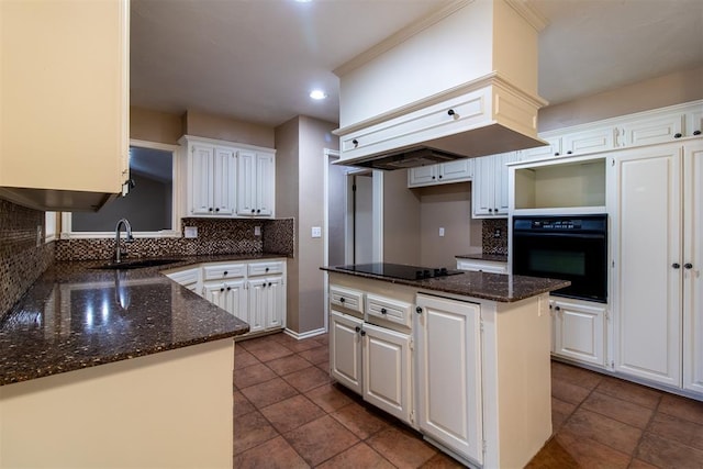 kitchen featuring tasteful backsplash, a sink, black appliances, dark stone counters, and white cabinetry