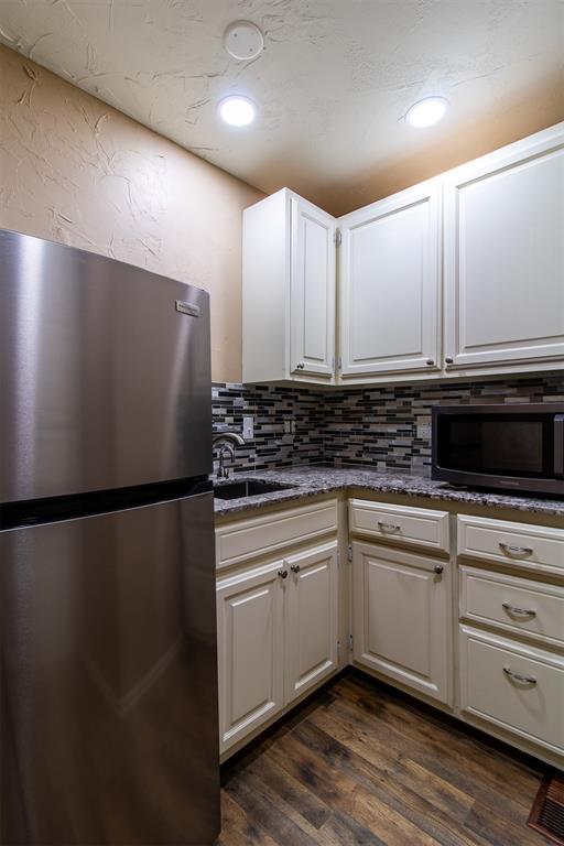kitchen featuring appliances with stainless steel finishes, tasteful backsplash, dark wood finished floors, a sink, and recessed lighting
