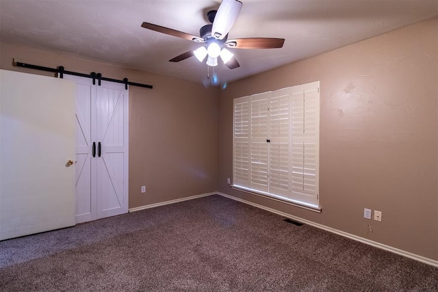 spare room featuring ceiling fan, carpet, a barn door, and visible vents