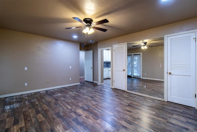spare room featuring baseboards, a ceiling fan, and dark wood-type flooring