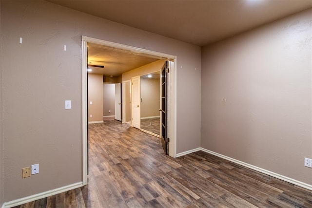 unfurnished room featuring dark wood-type flooring and baseboards