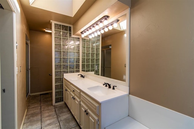 full bath with double vanity, a sink, tile patterned floors, and a shower stall